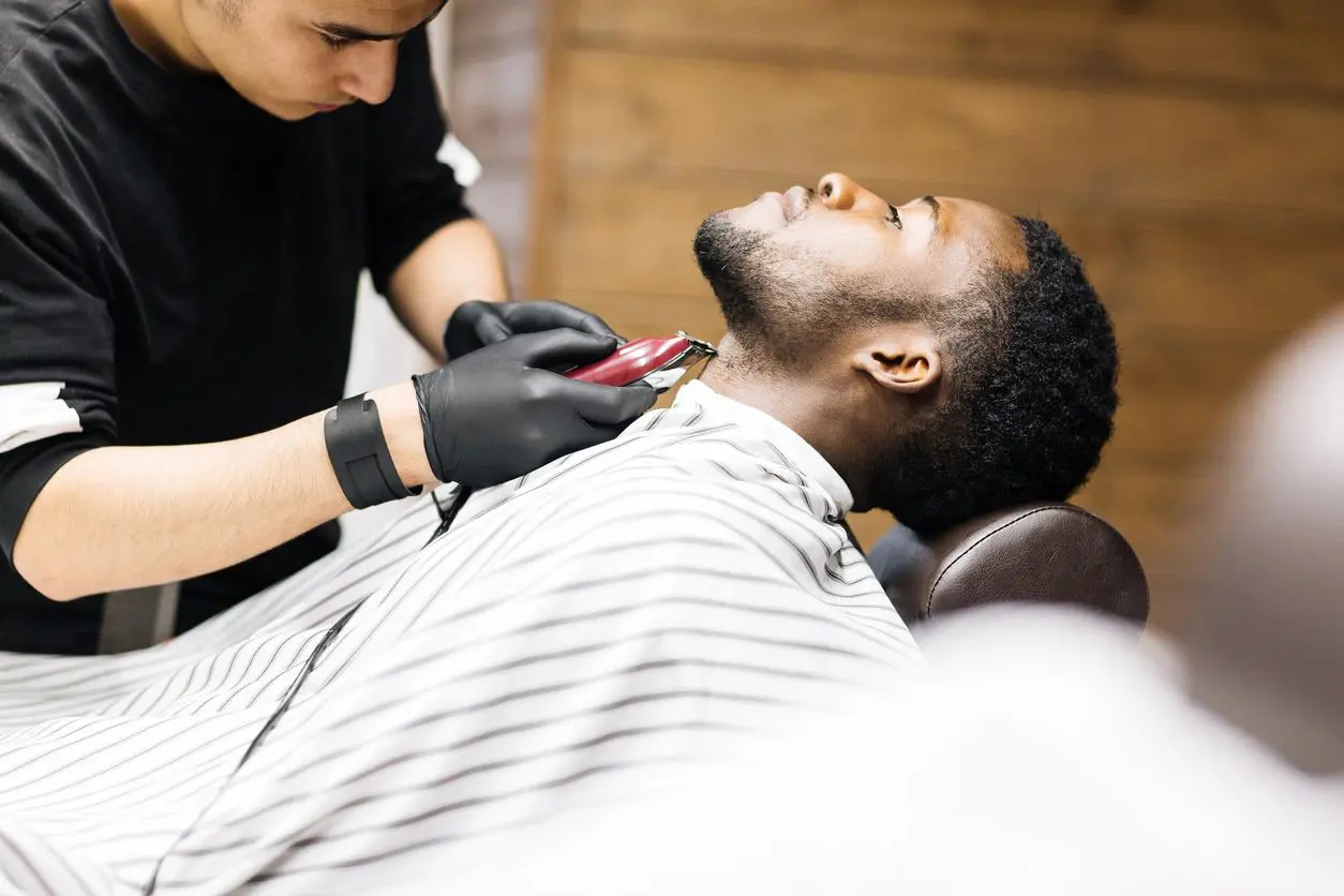 A man getting his teeth brushed by a barber